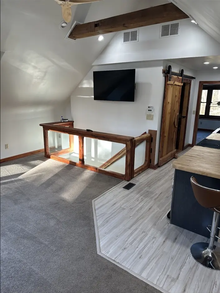 Completed loft interior with custom glass stair railing, barn door, and finished trim