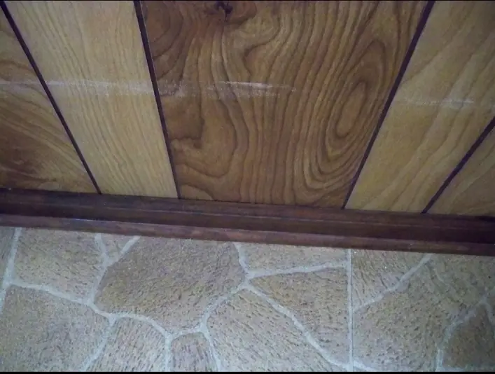 Wood paneling with a long horizontal adhesive streak before restoration